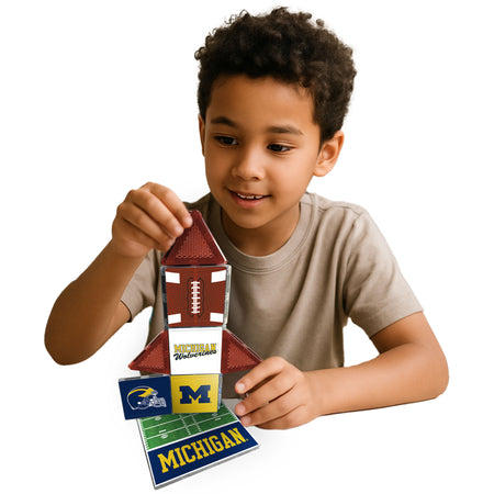 Child holding a football-themed building toy with Michigan branding