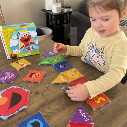 Child playing with educational magnetic tiles on a wooden table