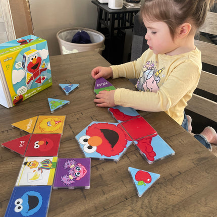 Child playing with colorful Elmo Magnetic tile set on a wooden table