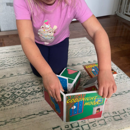 Child playing with a set of books on a rug