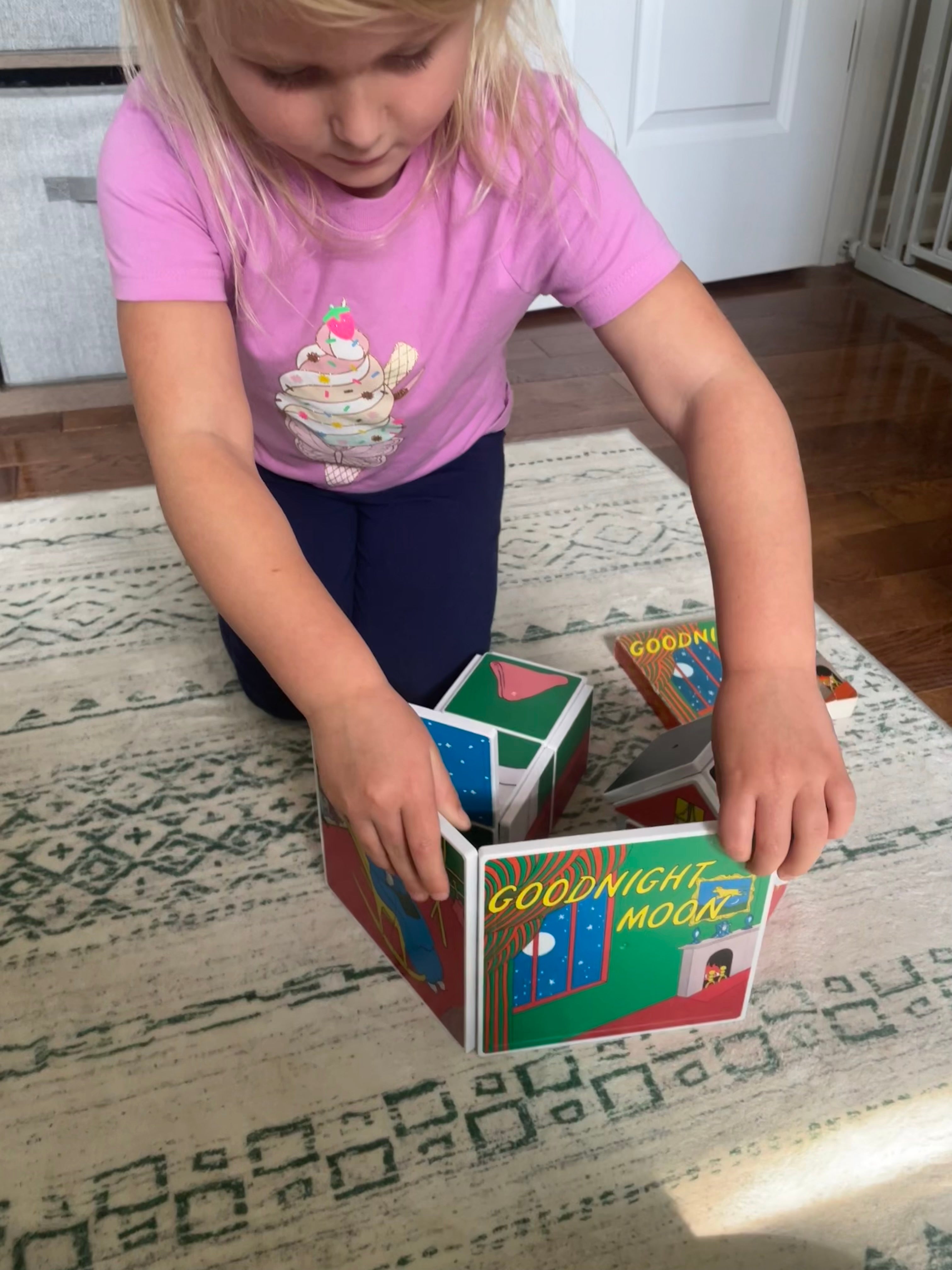 Child playing with a set of books on a rug
