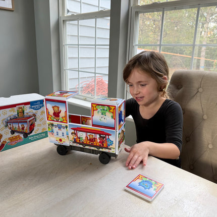 Child playing with a magnetic toy truck on a table next to its packaging