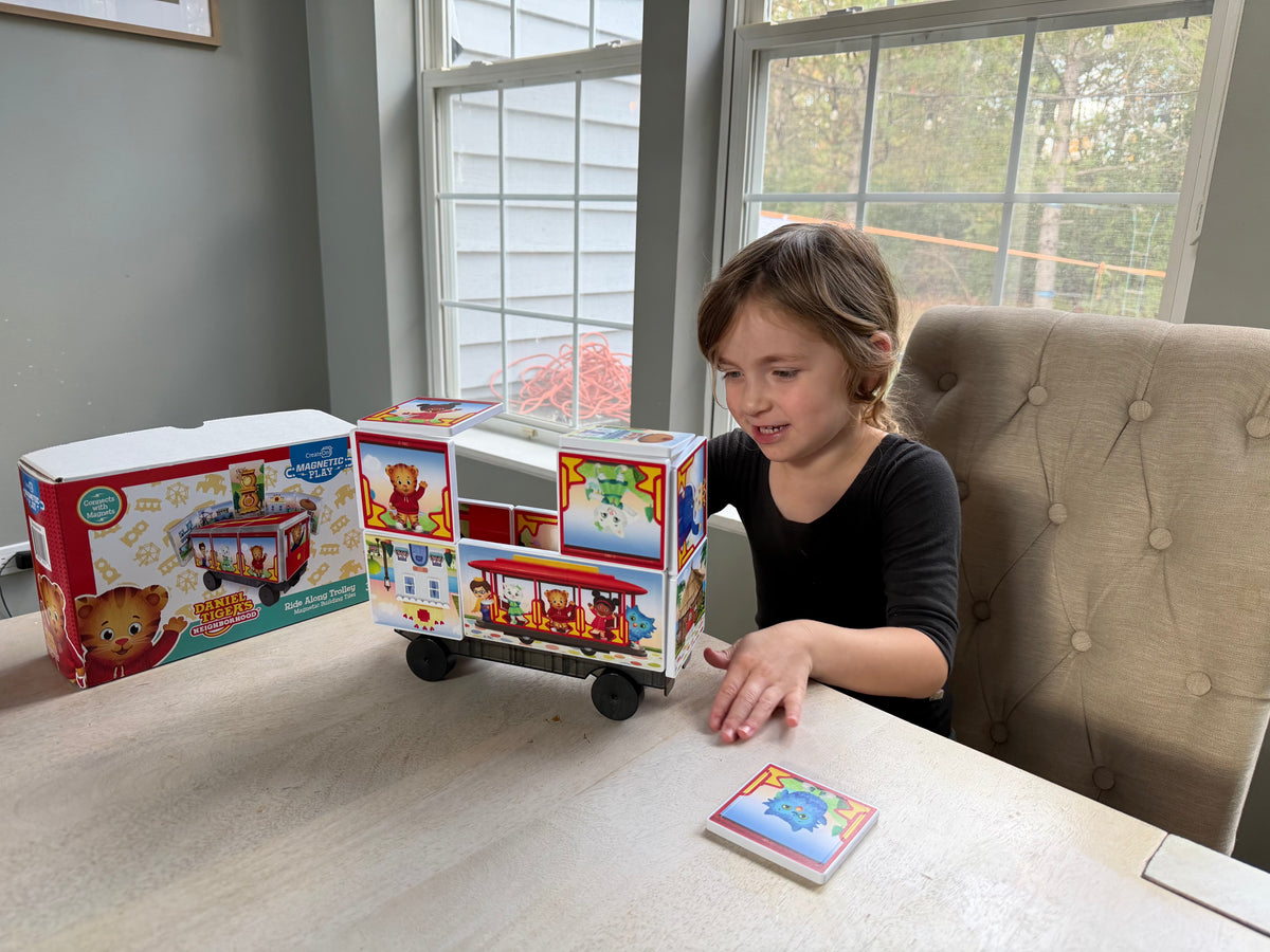 Child playing with a toy truck on a table next to its packaging