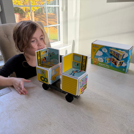 Child playing with a toy made from magnetic Tiles on a table.