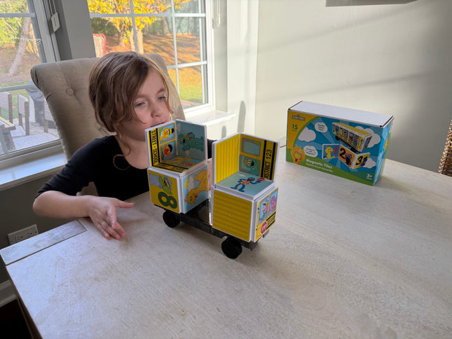 Child playing with a toy made from magnetic Tiles on a table.