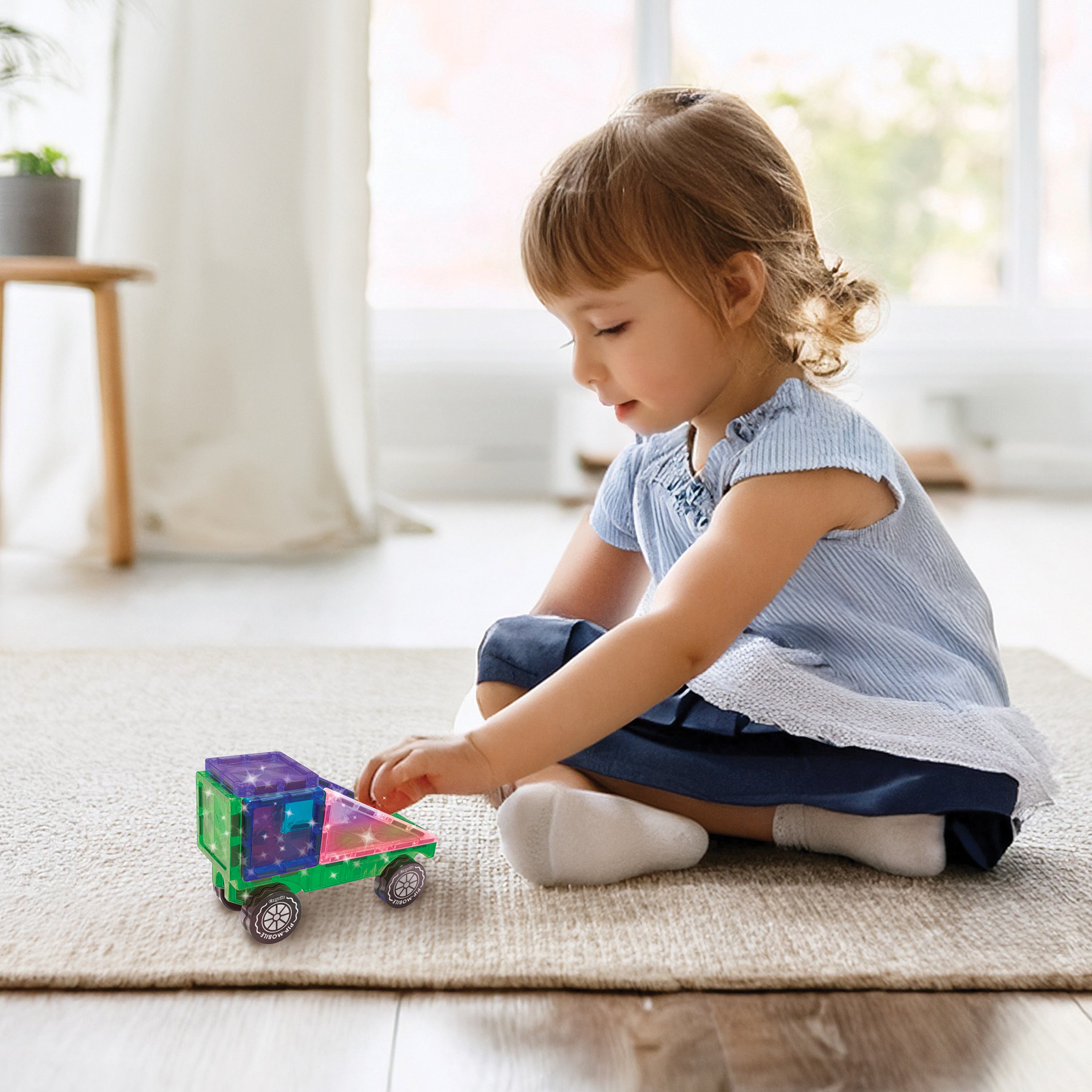 Child playing with a toy car on a rug in a bright room