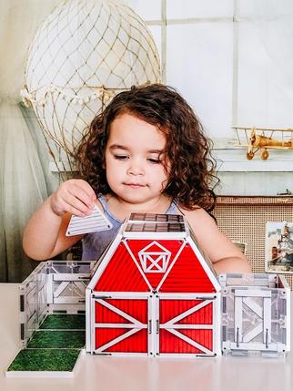 Child Playing with a Magnatiles Structure Set of Red Barn
